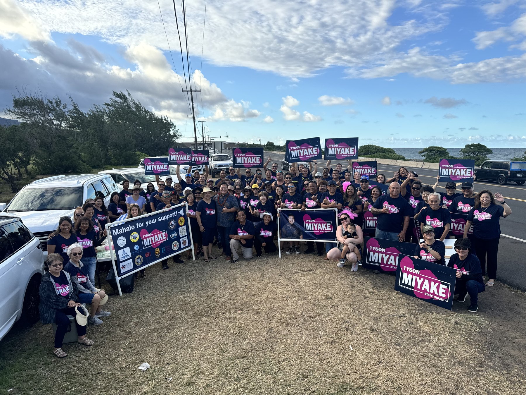 Team Miyake volunteers holding campaign signs near the coast